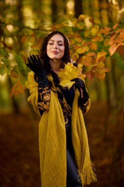 Battaniyeli güzel kadın sonbaharın tadını çıkarıyor ve yaprakların tadını çıkarıyor..