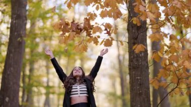 Sonbaharda yaprakları fırlatan ve doğanın tadını çıkaran güzel bir genç kadın.