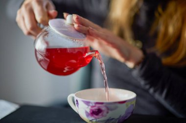 Kadının elleri çaydanlıktan bir fincana çay dolduruyor.