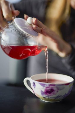Kadının elleri çaydanlıktan bir fincana çay dolduruyor.