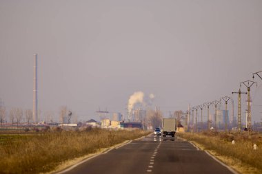 a road leading to an industrial center on a day with strong sunlight causing heat distortion of the image clipart