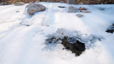 Bir dağ nehrinde buzun altından akan su.