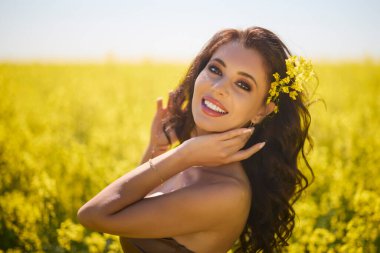 Güzel kadın çiçek açan kolza tohumu tarlasında poz veriyor.