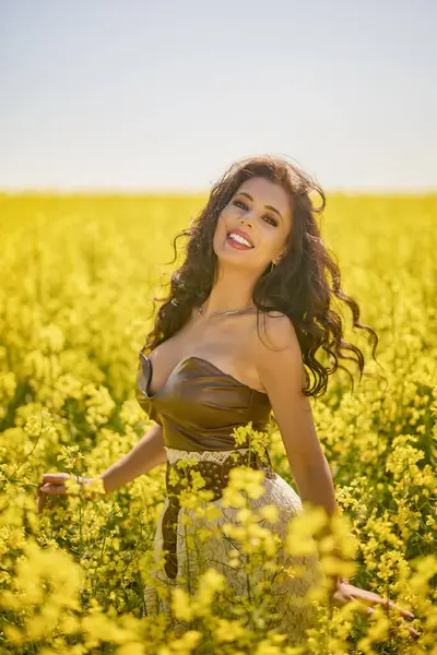 Güzel kadın çiçek açan kolza tohumu tarlasında poz veriyor.