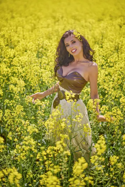 Güzel kadın çiçek açan kolza tohumu tarlasında poz veriyor.