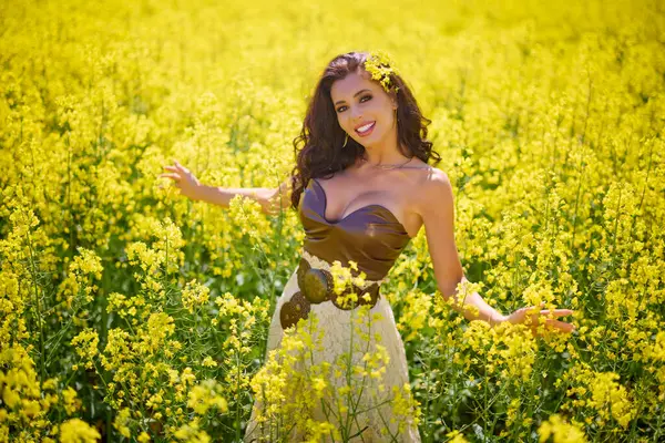 Güzel kadın çiçek açan kolza tohumu tarlasında poz veriyor.