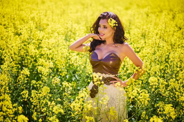 Güzel kadın çiçek açan kolza tohumu tarlasında poz veriyor.