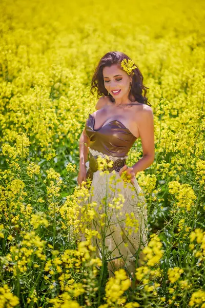 Güzel kadın çiçek açan kolza tohumu tarlasında poz veriyor.