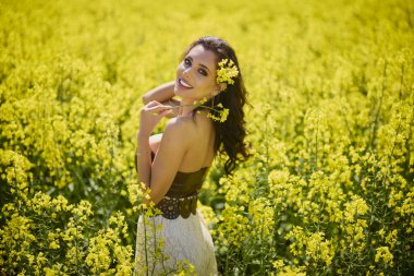 Güzel kadın çiçek açan kolza tohumu tarlasında poz veriyor.