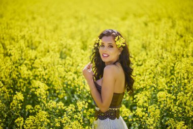 Güzel kadın çiçek açan kolza tohumu tarlasında poz veriyor.