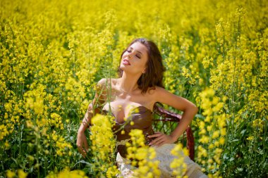 Güzel kadın çiçek açan kolza tohumu tarlasında poz veriyor.