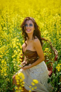 Güzel kadın çiçek açan kolza tohumu tarlasında poz veriyor.