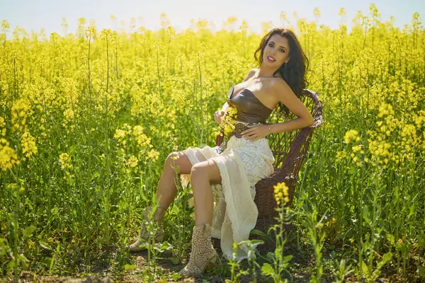 Güzel kadın çiçek açan kolza tohumu tarlasında poz veriyor.