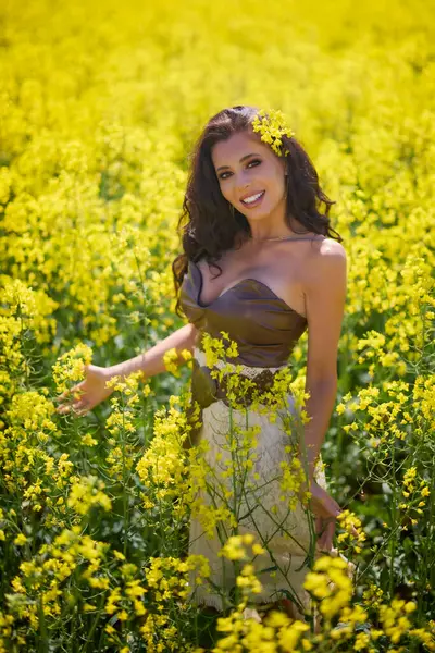 Güzel kadın çiçek açan kolza tohumu tarlasında poz veriyor.