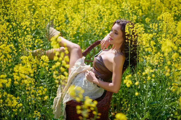 Güzel kadın çiçek açan kolza tohumu tarlasında poz veriyor.