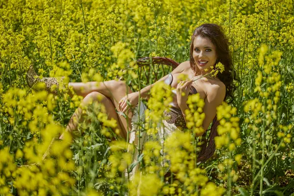 Güzel kadın çiçek açan kolza tohumu tarlasında poz veriyor.