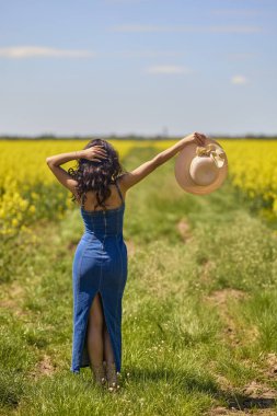 Şapkalı, uzun saçlı, yakut tohumu tarlasında kot giymiş güzel bir kadının portresi.