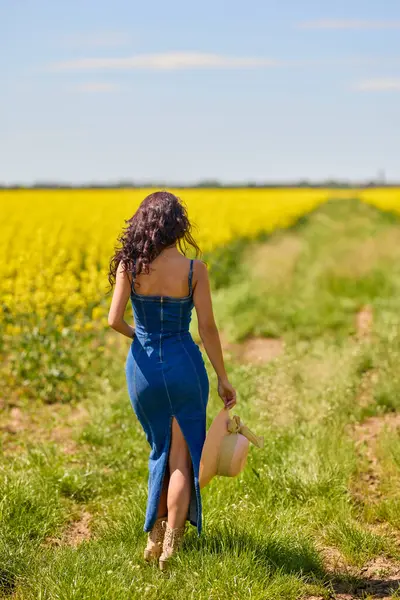 Şapkalı, uzun saçlı, yakut tohumu tarlasında kot giymiş güzel bir kadının portresi.