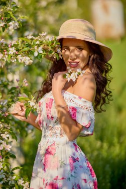 Çiçekli bir elma bahçesinde elbise giymiş güzel bir kadının portresi güneşli bir bahar gününün tadını çıkarıyor.