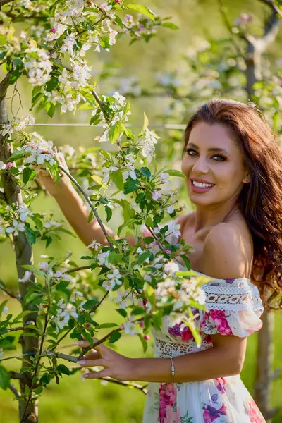 Çiçekli bir elma bahçesinde elbise giymiş güzel bir kadının portresi güneşli bir bahar gününün tadını çıkarıyor.