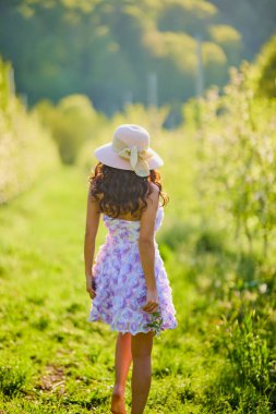 Arkaplanı bulanık, çiçek açmış bir elma bahçesinde güzel bir kadının portresi.