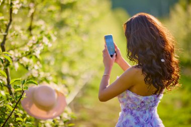 Arkaplanı bulanık, çiçek açmış bir elma bahçesinde güzel bir kadının portresi.