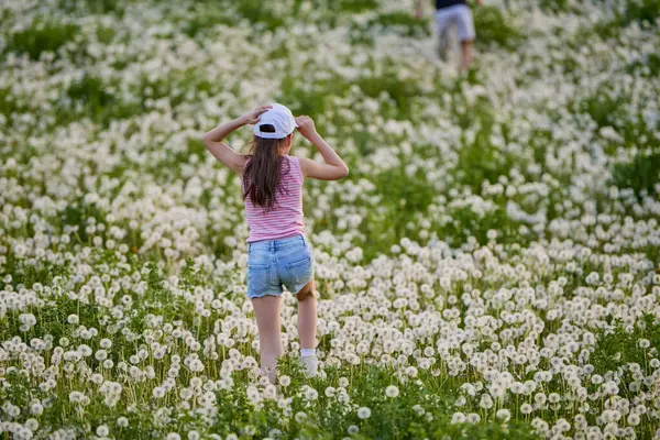 Bir bahar günü karahindiba otlağında oynayan tatlı küçük bir kız.