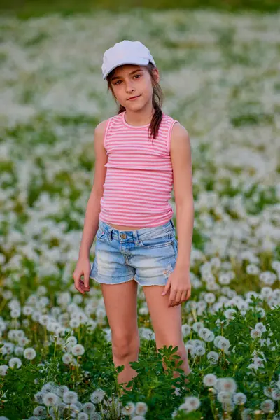 Bir bahar günü karahindiba otlağında oynayan tatlı küçük bir kız.