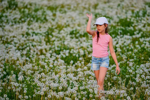 Bir bahar günü karahindiba otlağında oynayan tatlı küçük bir kız.