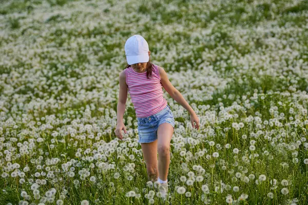 Bir bahar günü karahindiba otlağında oynayan tatlı küçük bir kız.
