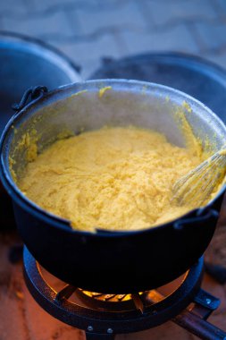 Büyük bir tencere ve ateşte pişen polenta.