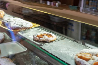 Vitrinde puf böreği ve kayısı olan bir tatlı.