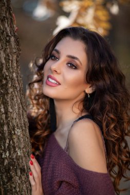 Güzel bir kadının portresi makyajlı, bir ağacın dallarında poz veriyor.