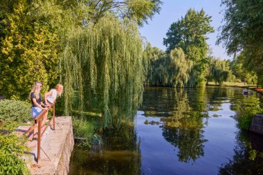İki orta yaşlı kız kardeş bir yaz sabahını parkta dinlenerek ve eğlenerek geçiriyorlar..
