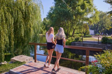 İki orta yaşlı kız kardeş bir yaz sabahını parkta dinlenerek ve eğlenerek geçiriyorlar..