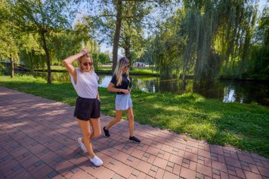 İki orta yaşlı kız kardeş bir yaz sabahını parkta dinlenerek ve eğlenerek geçiriyorlar..