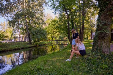 İki orta yaşlı kız kardeş bir yaz sabahını parkta dinlenerek ve eğlenerek geçiriyorlar..