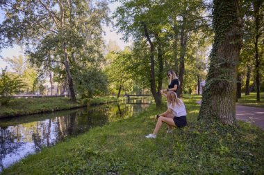 İki orta yaşlı kız kardeş bir yaz sabahını parkta dinlenerek ve eğlenerek geçiriyorlar..