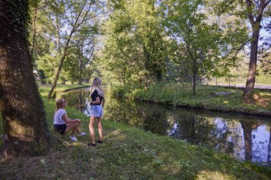 İki orta yaşlı kız kardeş bir yaz sabahını parkta dinlenerek ve eğlenerek geçiriyorlar..