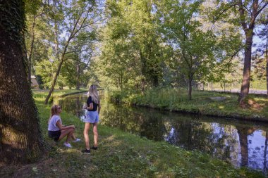 İki orta yaşlı kız kardeş bir yaz sabahını parkta dinlenerek ve eğlenerek geçiriyorlar..