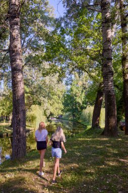 İki orta yaşlı kız kardeş bir yaz sabahını parkta dinlenerek ve eğlenerek geçiriyorlar..