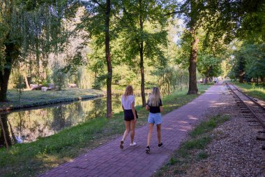 İki orta yaşlı kız kardeş bir yaz sabahını parkta dinlenerek ve eğlenerek geçiriyorlar..