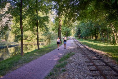 İki orta yaşlı kız kardeş bir yaz sabahını parkta dinlenerek ve eğlenerek geçiriyorlar..