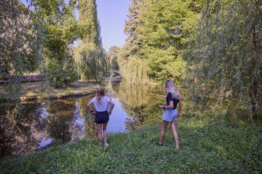 İki orta yaşlı kız kardeş bir yaz sabahını parkta dinlenerek ve eğlenerek geçiriyorlar..