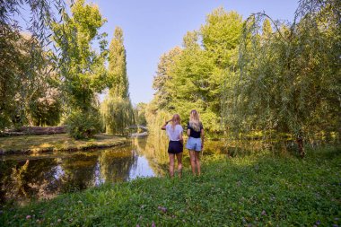 İki orta yaşlı kız kardeş bir yaz sabahını parkta dinlenerek ve eğlenerek geçiriyorlar..