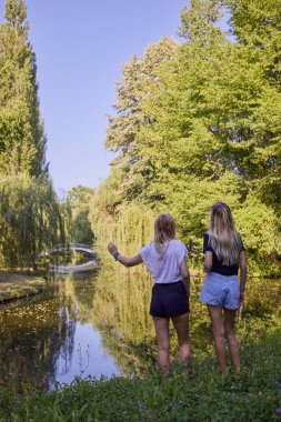 İki orta yaşlı kız kardeş bir yaz sabahını parkta dinlenerek ve eğlenerek geçiriyorlar..