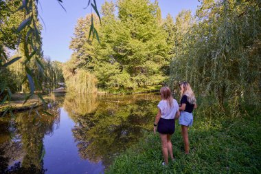 İki orta yaşlı kız kardeş bir yaz sabahını parkta dinlenerek ve eğlenerek geçiriyorlar..