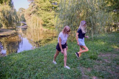 İki orta yaşlı kız kardeş bir yaz sabahını parkta dinlenerek ve eğlenerek geçiriyorlar..