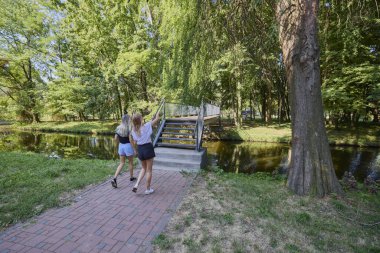 İki orta yaşlı kız kardeş bir yaz sabahını parkta dinlenerek ve eğlenerek geçiriyorlar..