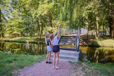 İki orta yaşlı kız kardeş bir yaz sabahını parkta dinlenerek ve eğlenerek geçiriyorlar..